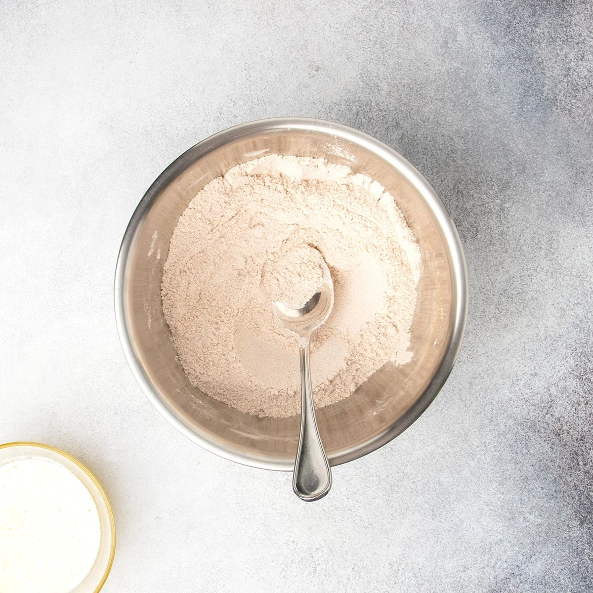 Brown sugar, cinnamon, and flour mixture stirred together in a metal mixing bowl with a metal mixing spoon.
