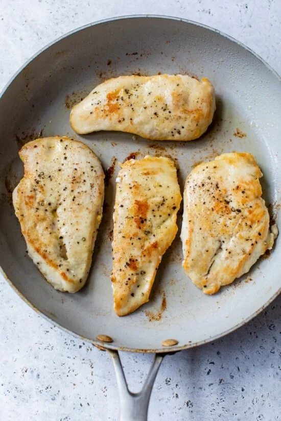 Browned chicken breasts in a skillet.