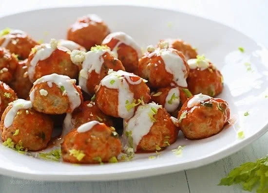 Buffalo Chicken Meatballs are perfect for football season! Made with minced celery and carrots hidden inside, topped with hot sauce, and homemade blue cheese dressing – yum!