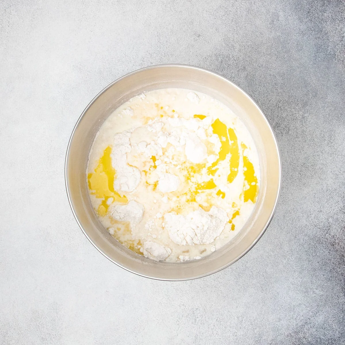 Butter, milk, and egg whites added to the flour mixture in a metal bowl before mixing.