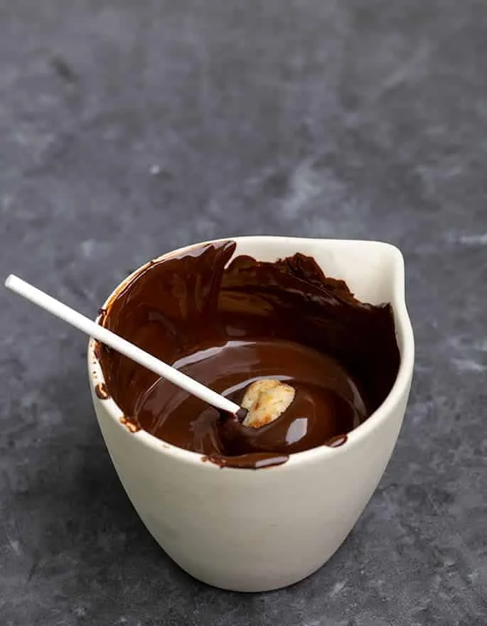 Cake pop on lollipop stick being dipped in melted chocolate