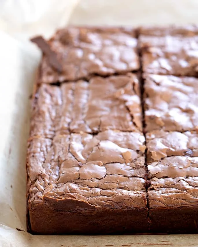 Chewy, rich brownies in a baking tin lined with baking paper.