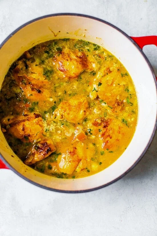 Chicken and rice simmering in broth in a large pot.