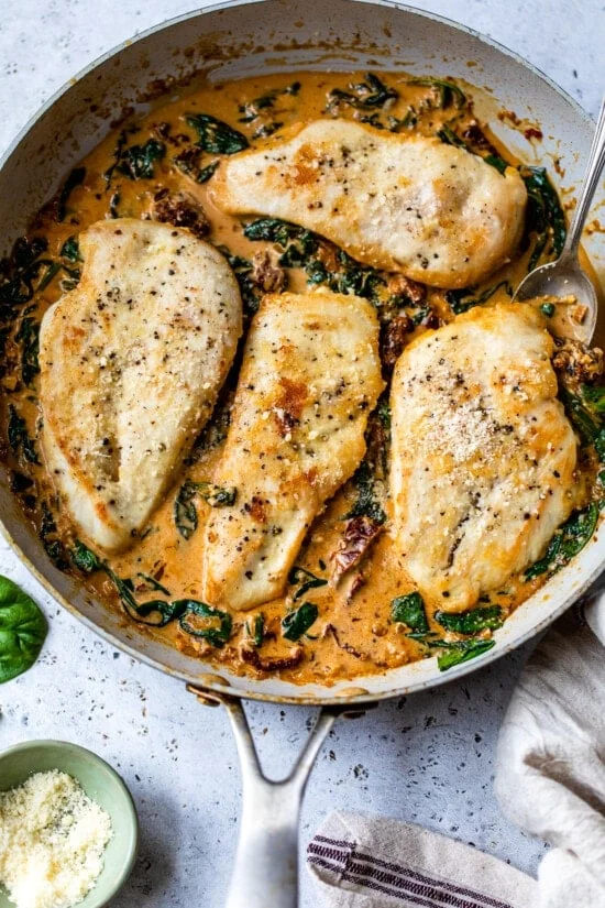 Chicken breasts added to Marry Me Chicken sauce in a skillet.