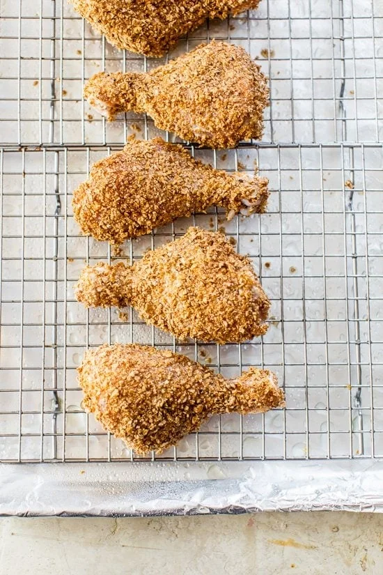 Chicken drumsticks on a wire rack before baking.
