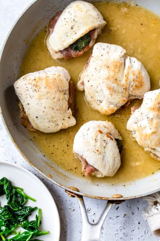 Chicken saltimbocca cooking in skillet with white wine sauce