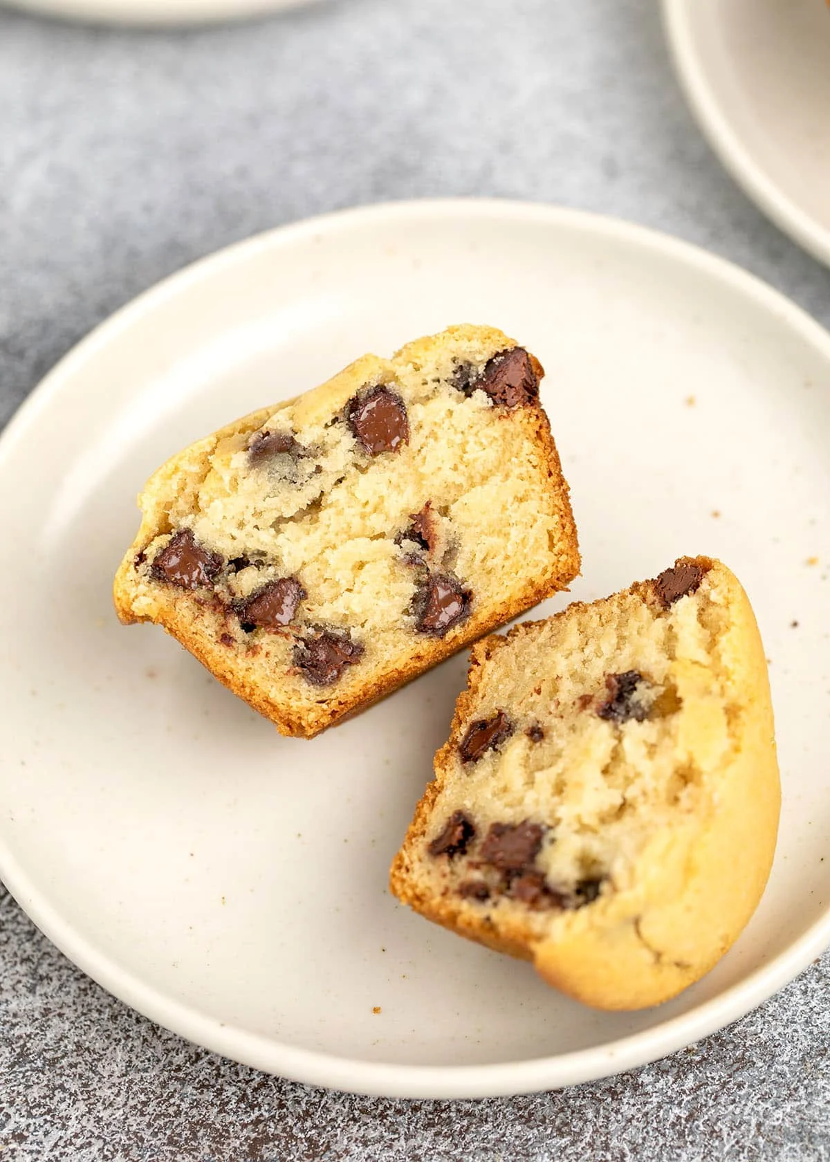 chocolate chip muffin sliced in half on white plate