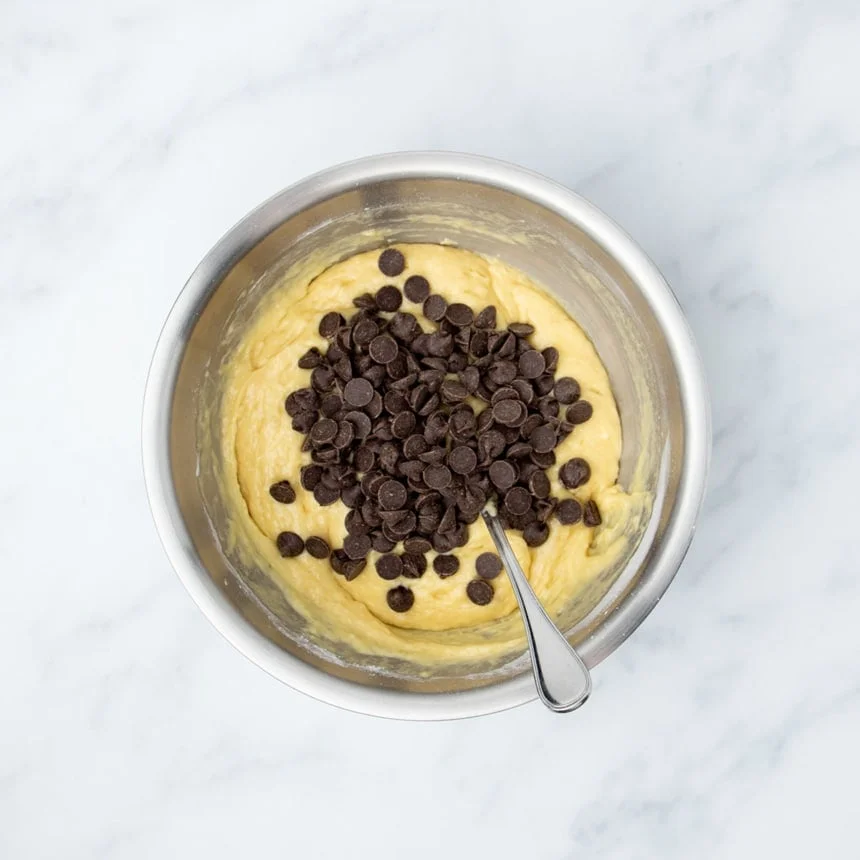 chocolate chips on top of yellow muffin batter in mixing bowl