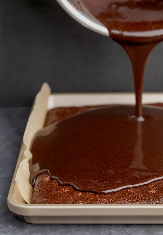 Chocolate icing pouring on chocolate sheet cake in sheet pan