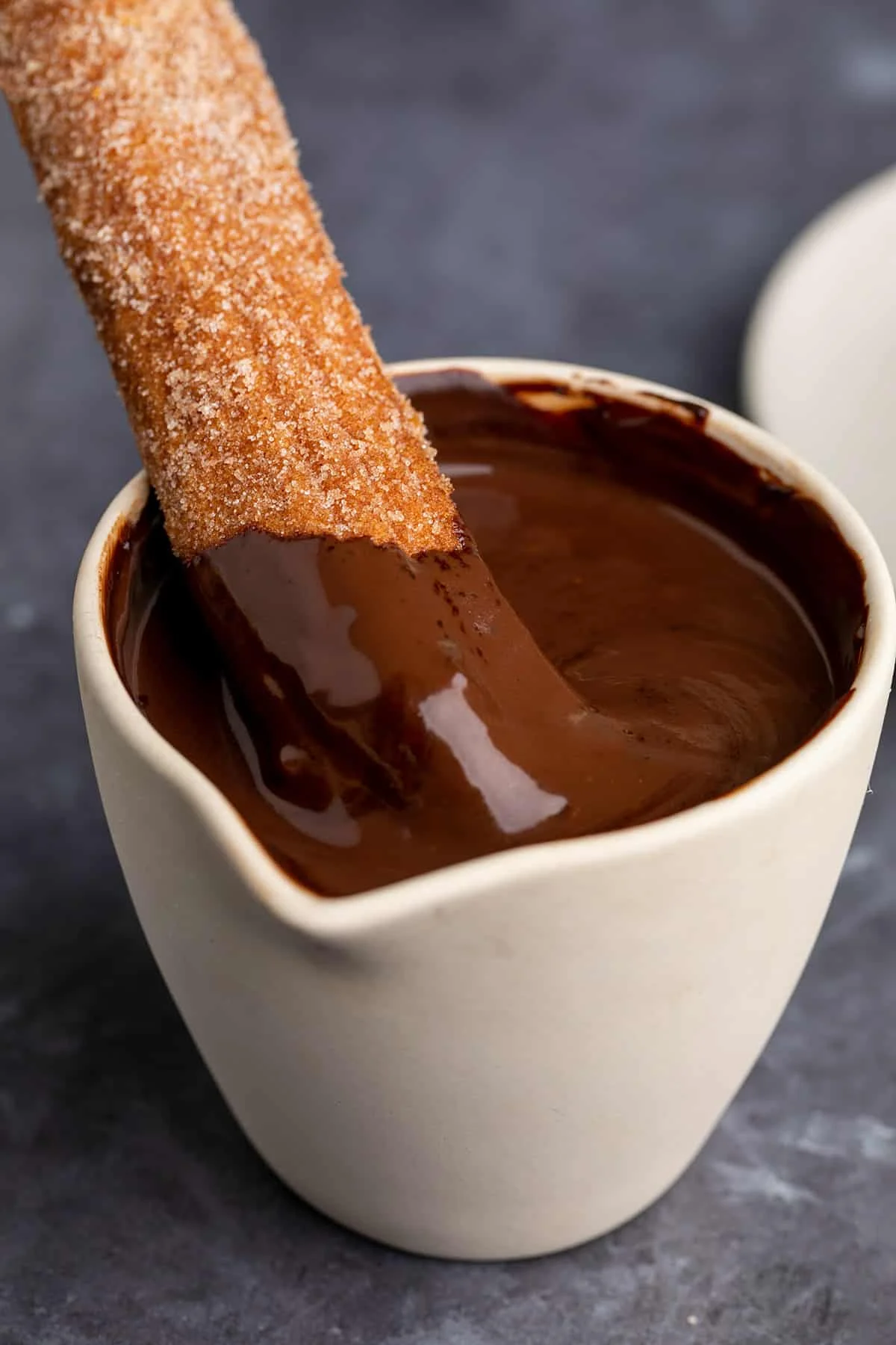 Churro sitting in chocolate sauce in jar