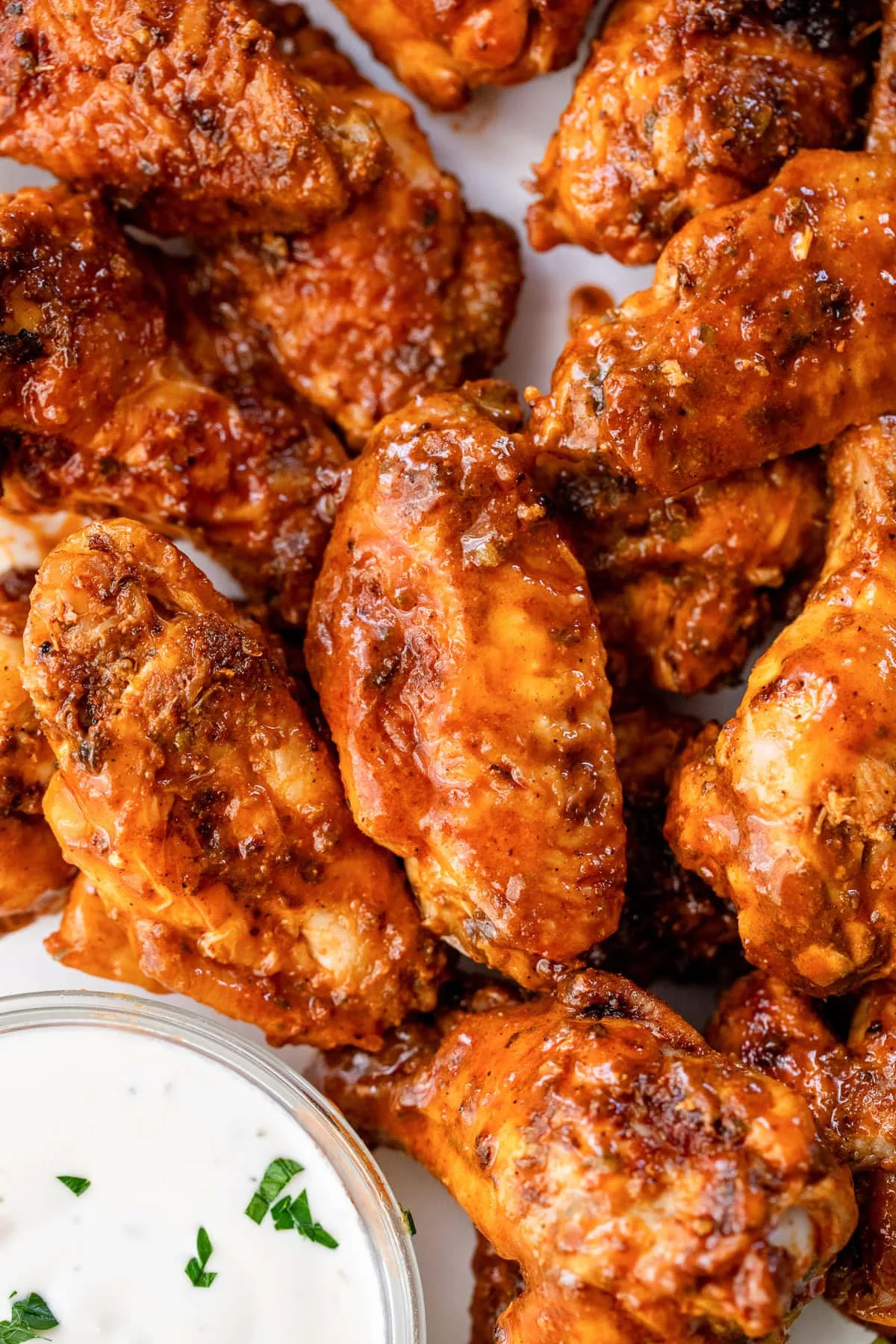 Close up of baked buffalo wings next to a bowl of blue cheese dressing.