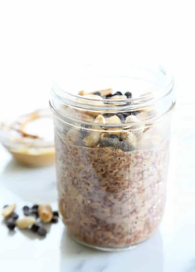Close up of chocolate overnight oats and chocolate chips in a jar on marble surface 
