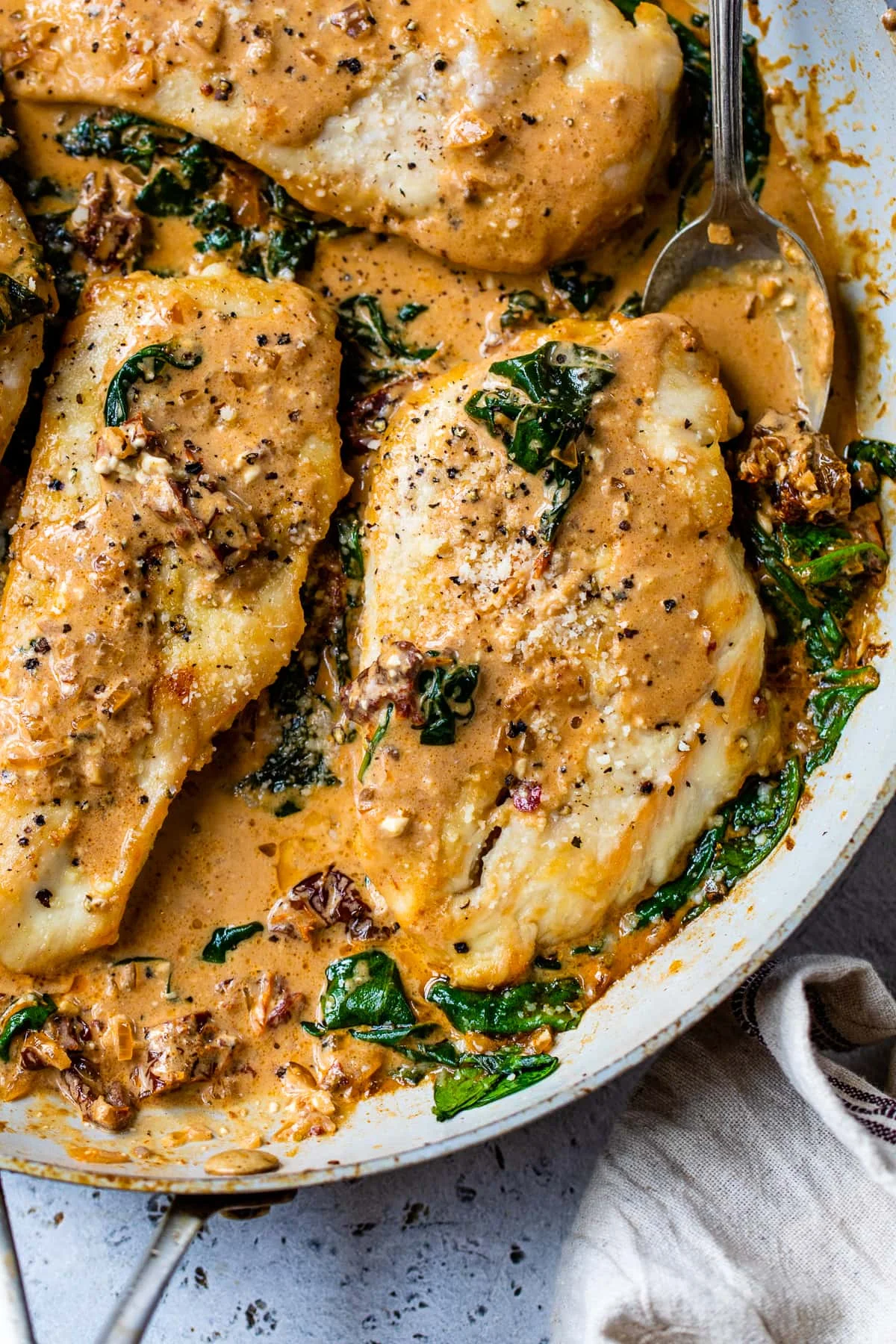 Close up of Marry Me Chicken with creamy tomato sauce and spinach in a skillet.