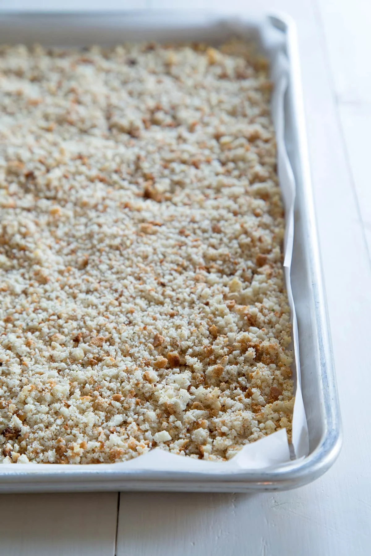 Close up of toasted crumbs on metal tin lined with white paper.