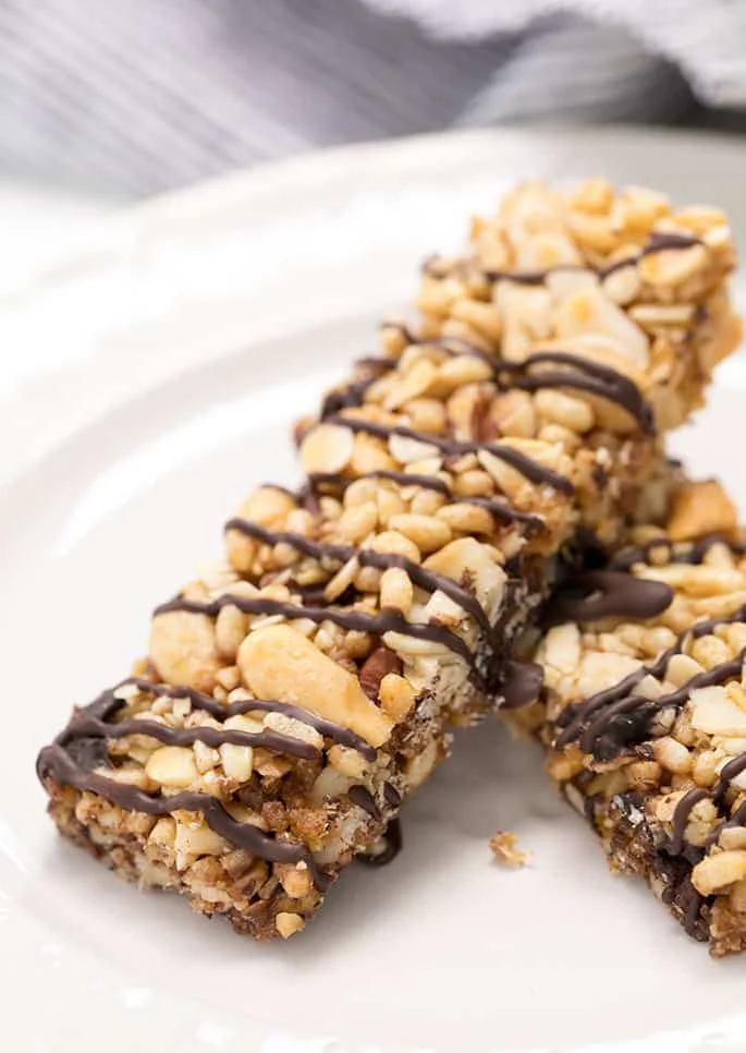 Closeup image of 2 light colored homemade cereal bars with a drizzle of chocolate on a white platter