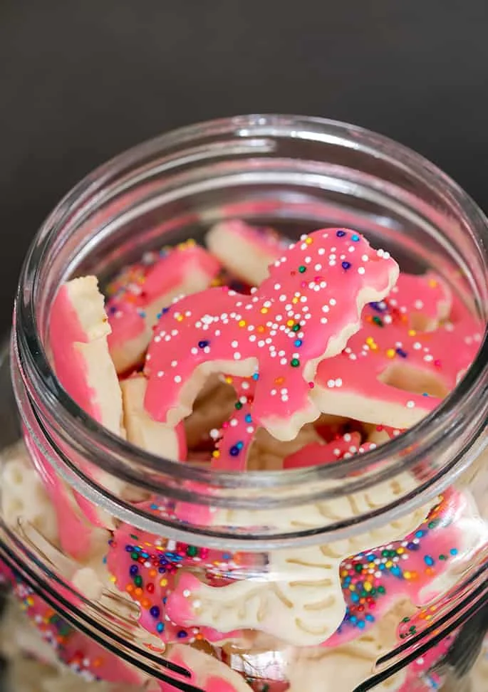 Closeup image of lion shaped animal cracker with pink frosting and rainbow nonpareils.