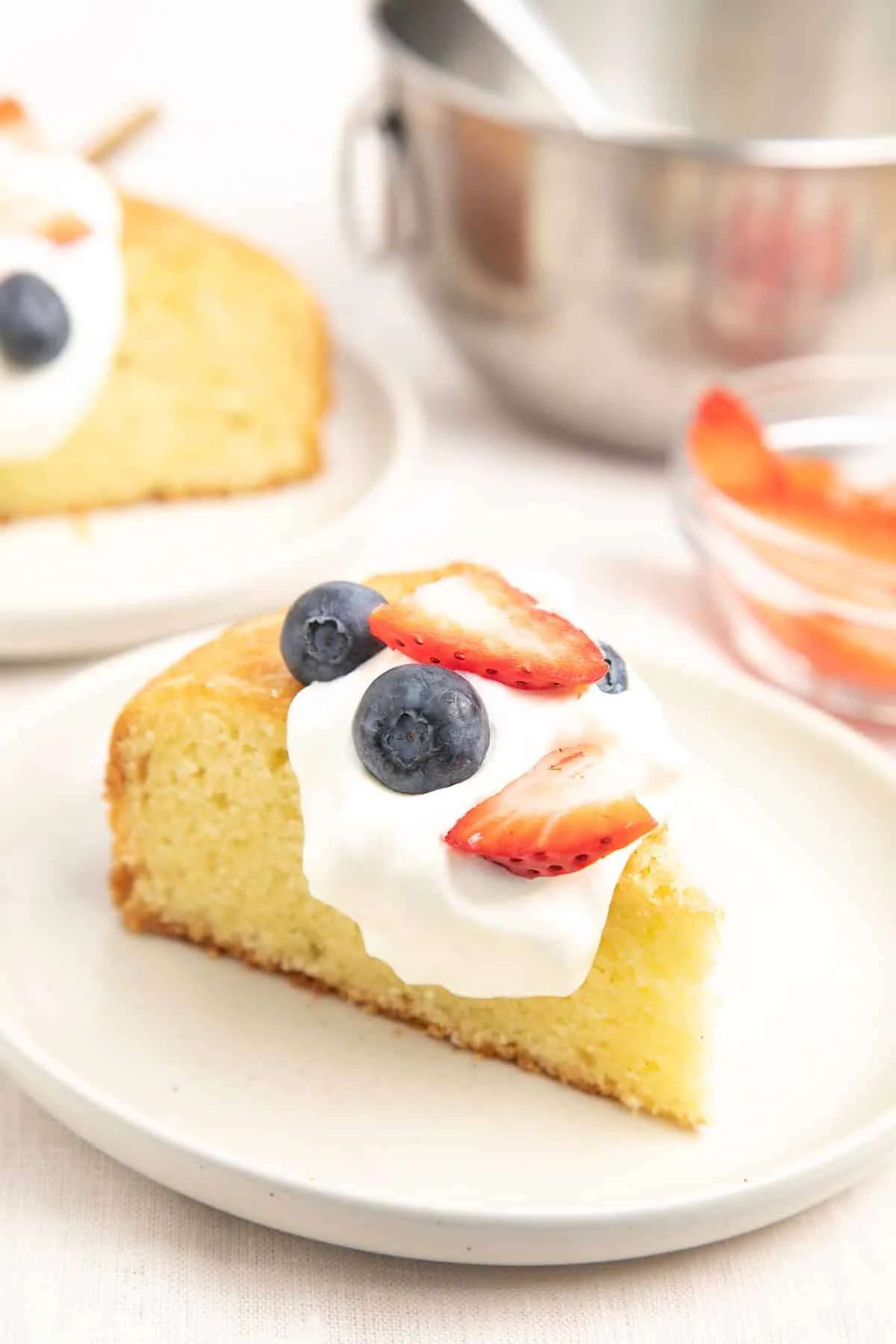 Closeup image of slice of olive oil cake with berries and cream