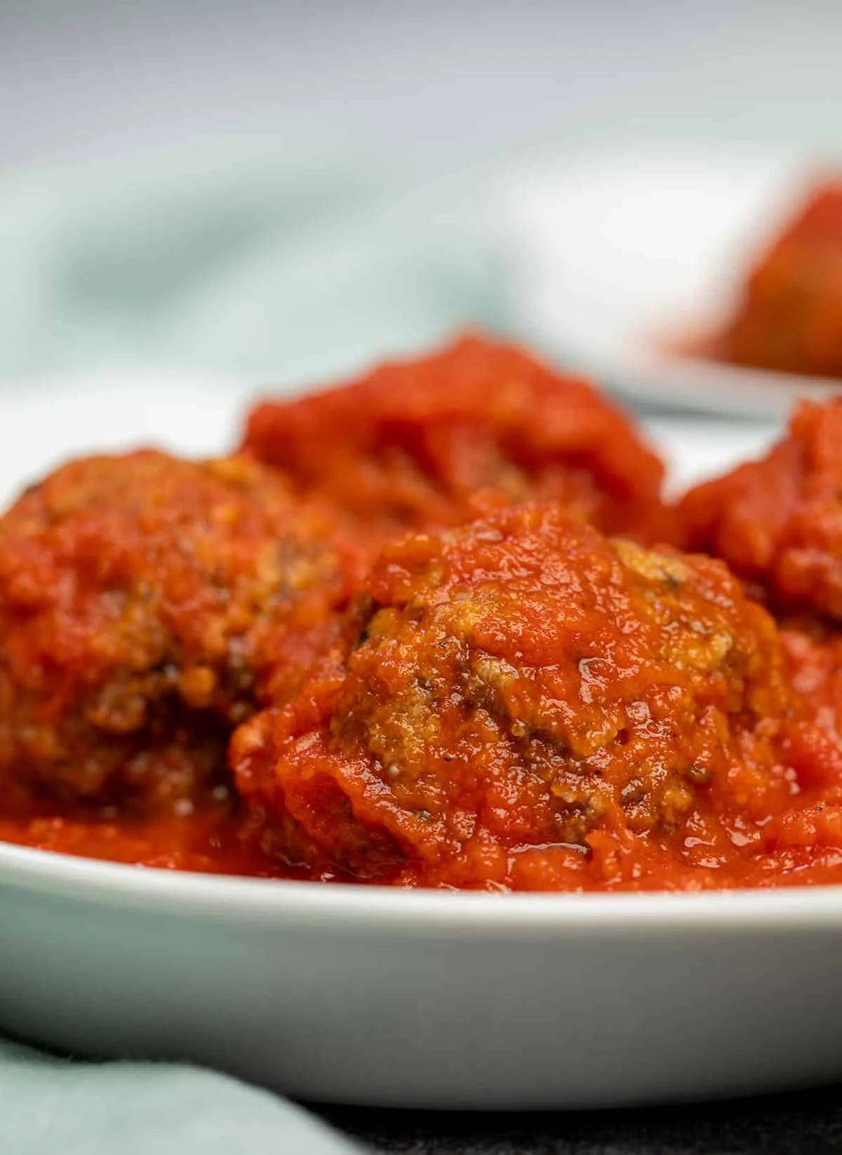 Closeup of 4 meatballs in white dish.