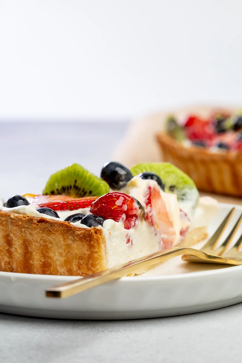 closeup of gold for, on white plate with slice of fruit tart