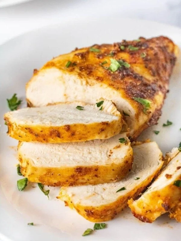 Closeup of sliced air fryer chicken breasts that were cooked from chicken on a white plate