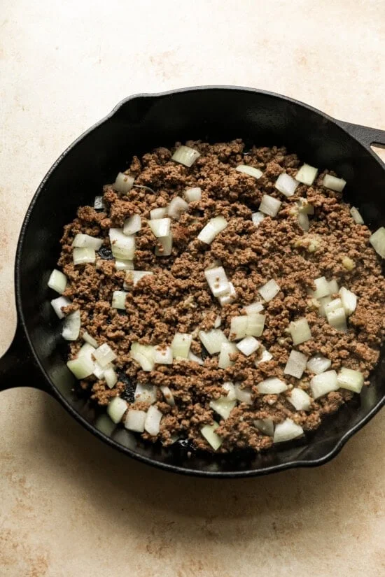 Cook the ground beef, add onions and garlic.