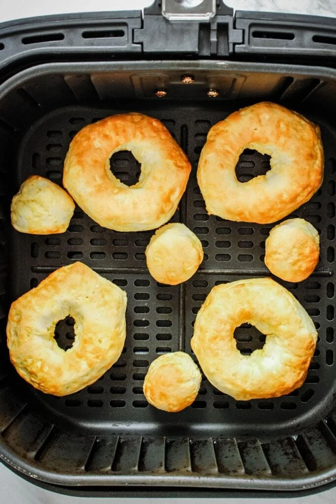 Cooked donuts in the air fryer basket.