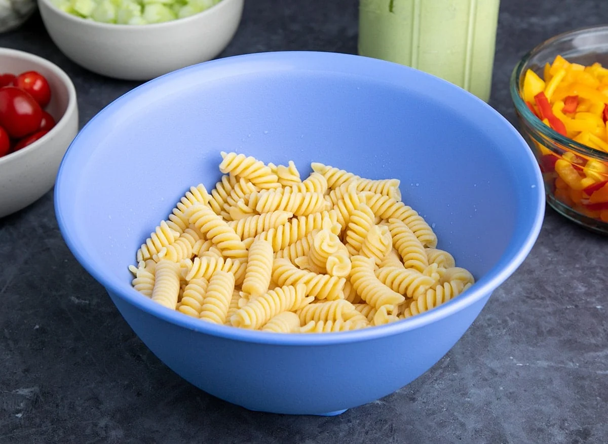 cooked fusilli pasta in blue serving bowl on gray surface
