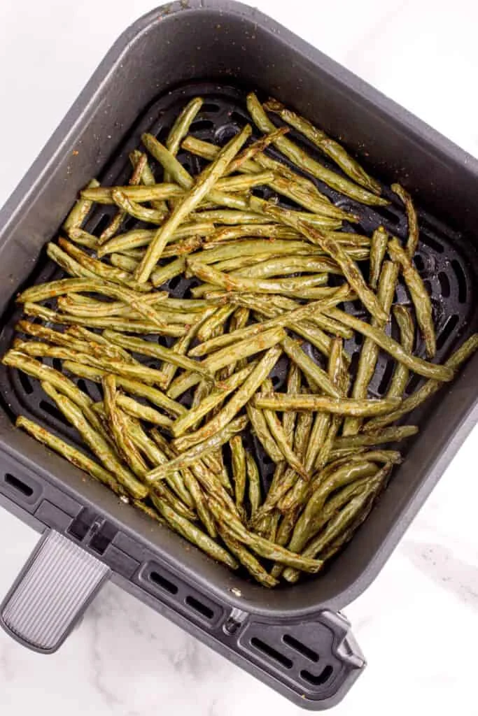 Cooked green beans in the air fryer basket.