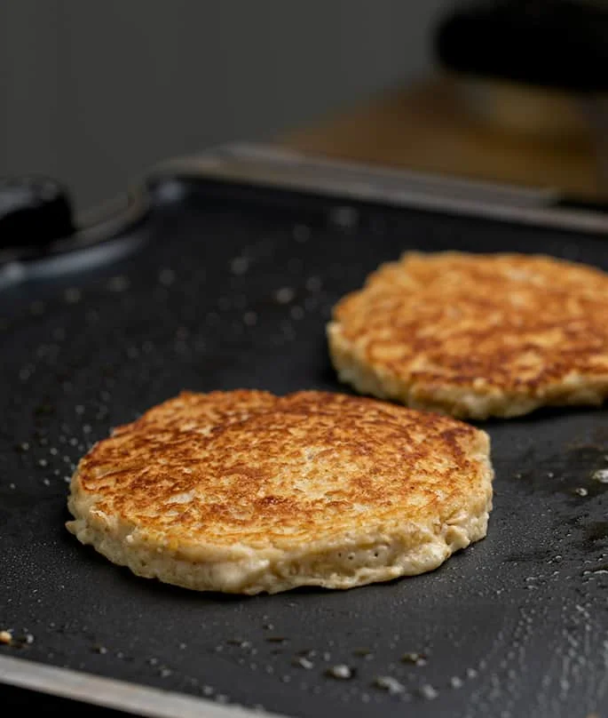 Cooked oatmeal pancakes on greased skillet