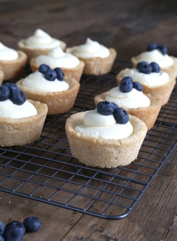 Cookie cups with cheesecake filling and blueberries on black tray