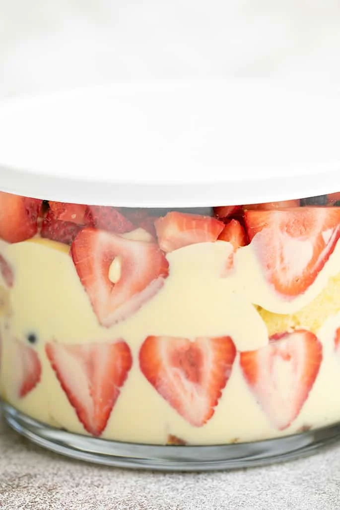 Custard, pound cake, and strawberries in glass bowl with white lid