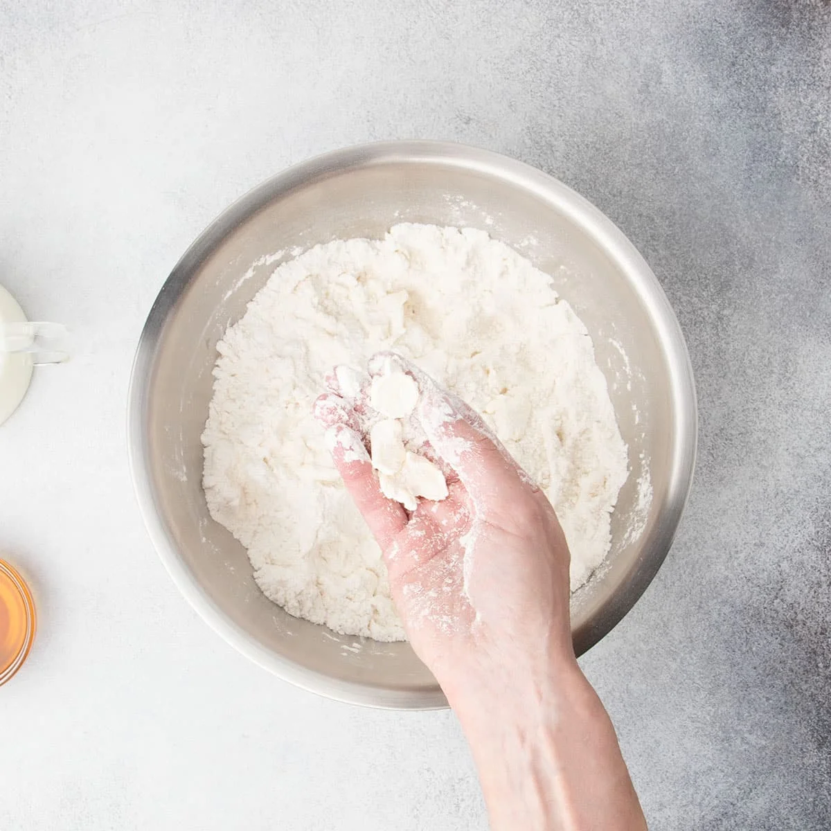 Cutting cold butter into gluten free flour with fingers in a metal mixing bowl.