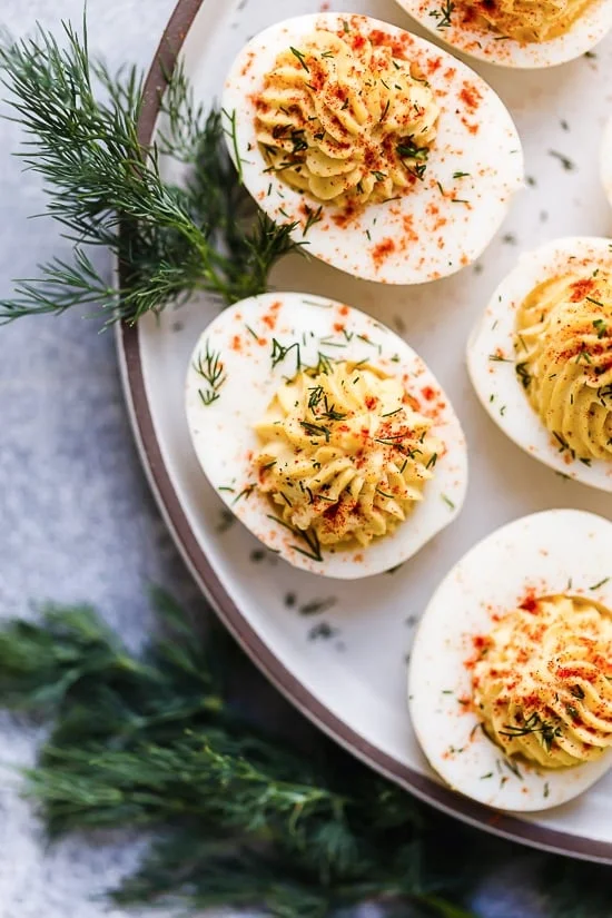 Deviled eggs topped with paprika on a platter