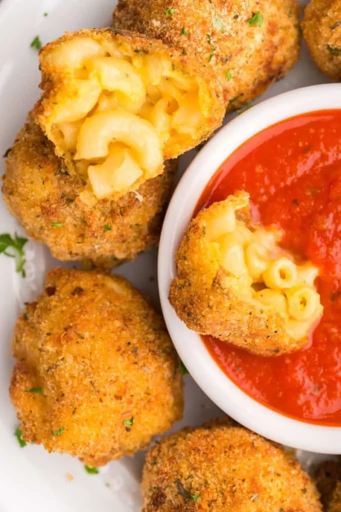 dipping mac and cheese bite into sauce