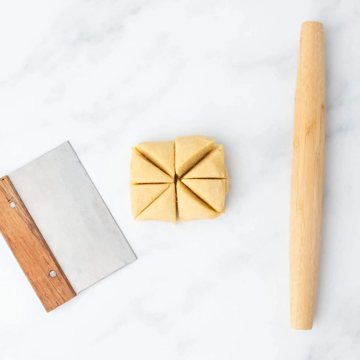 Dough divided into 8 wedges with a bench scraper beside it.