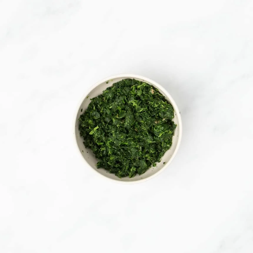 dried green chopped spinach in small light tan bowl