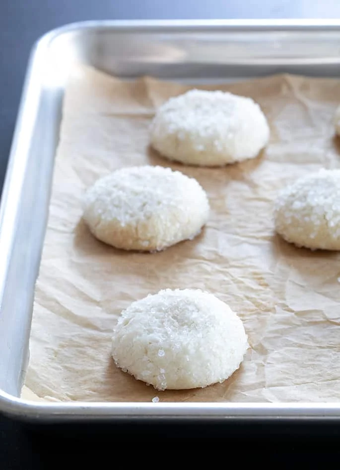Drop sugar cookies with white sugar on a tray.