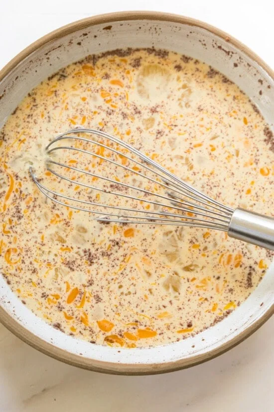 Egg custard in a bowl with a whisk.