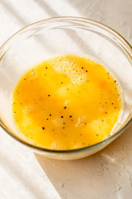 Eggs mixed with salt and pepper in bowl
