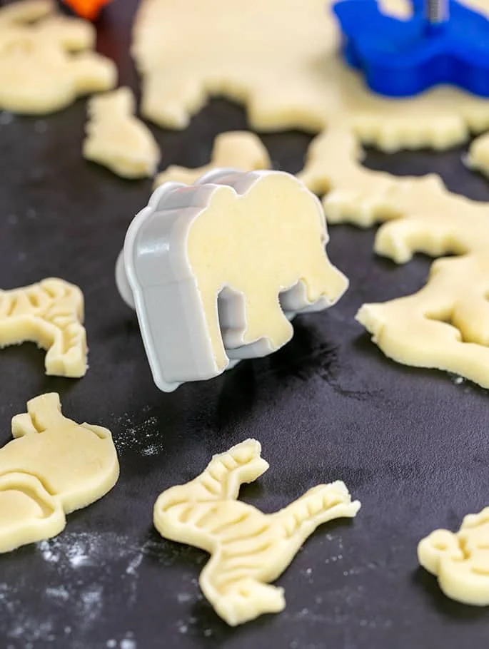 Elephant cookie cutter with cut dough in it on black board.