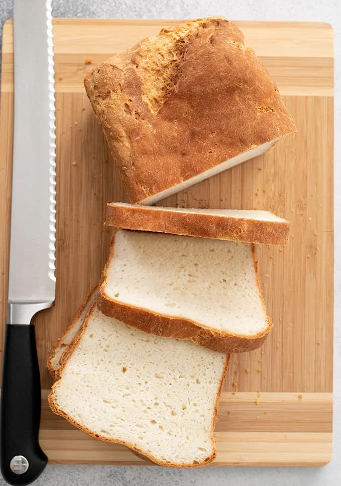 English muffin bread loaf partially sliced on a cutting board overhead image.