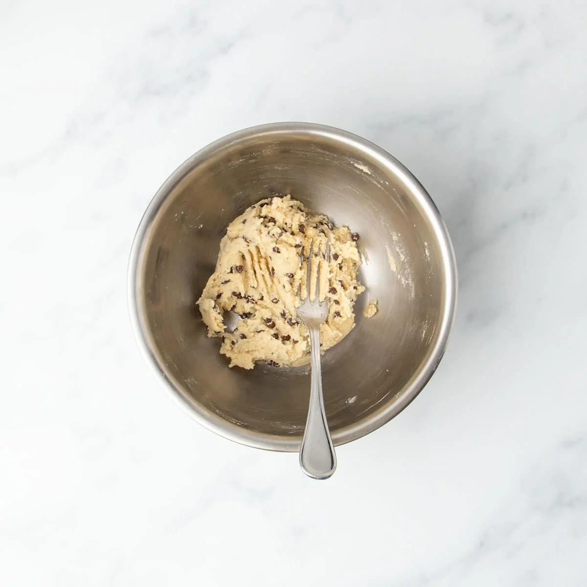 Finished cookie dough in bowl with mini chocolate chips mixed throughout.
