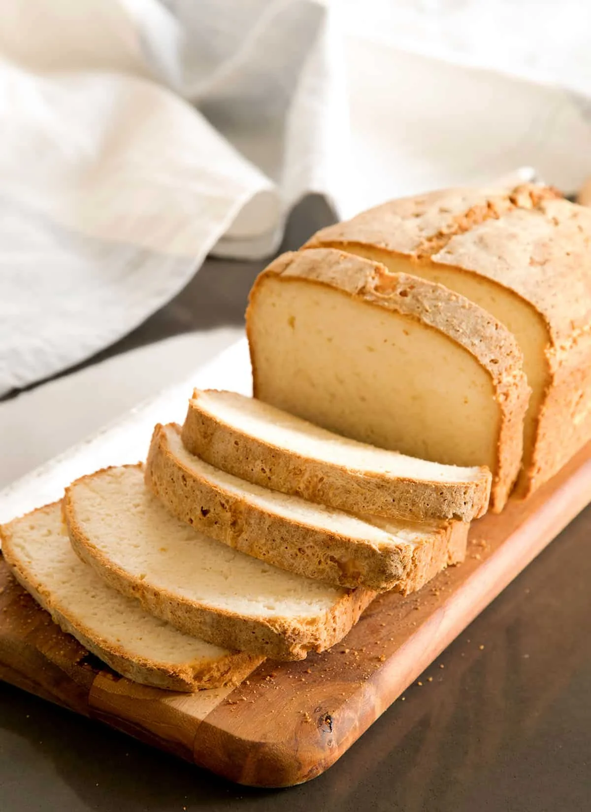 Freshly sliced bread sitting on a brown cutting board.