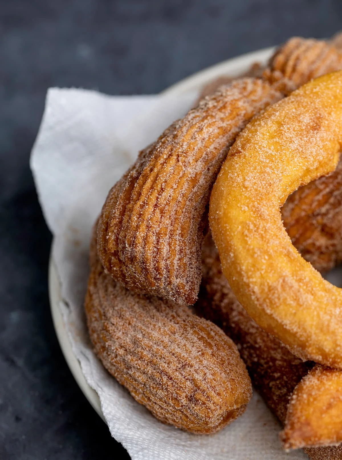 Fried churros on paper towels on white plate