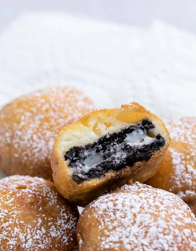 Fried Oreo cut in half with melting inside on top of whole fried Oreos