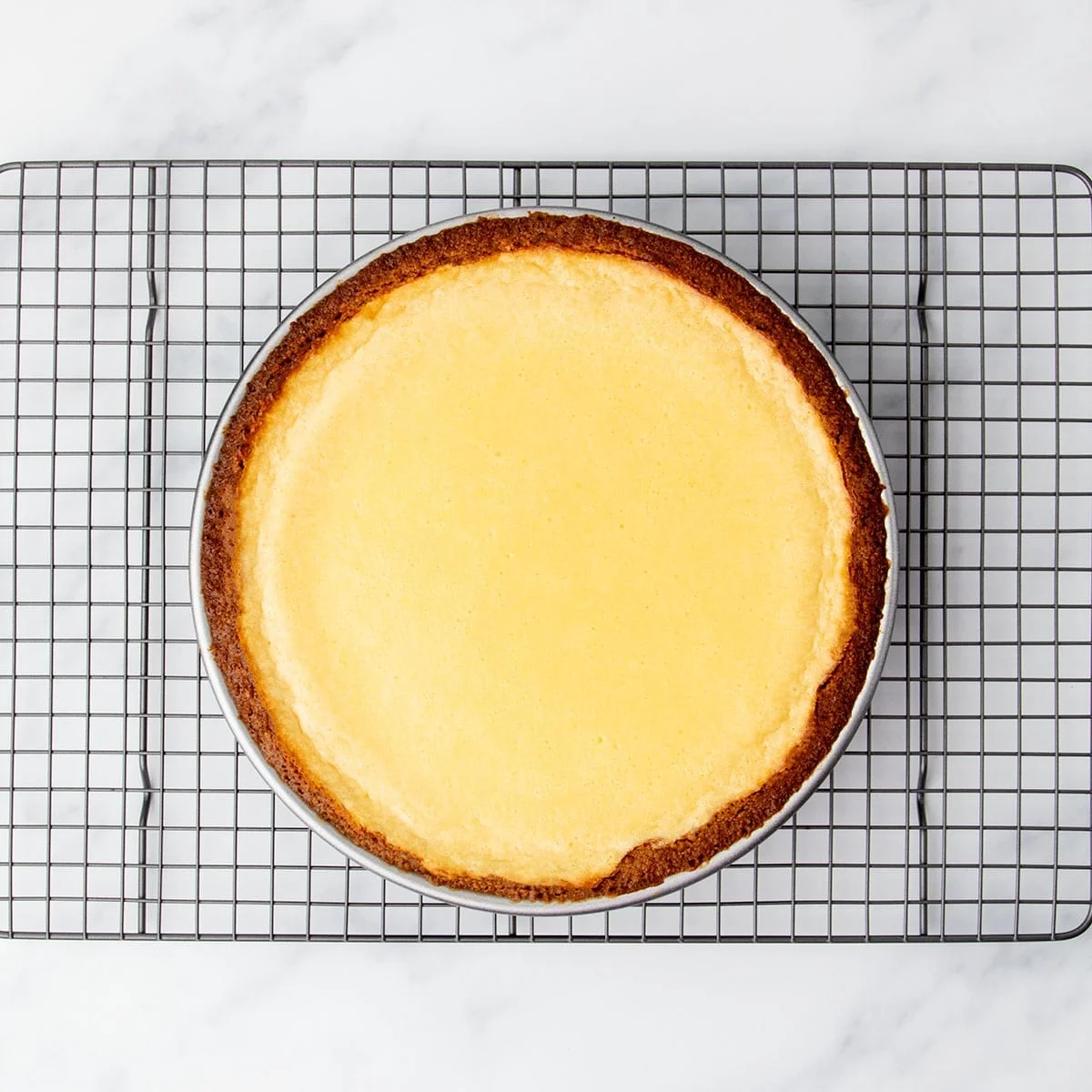 Fully baked lemon pie cooling on a wire rack, with a lightly golden top and crisp crust edges.