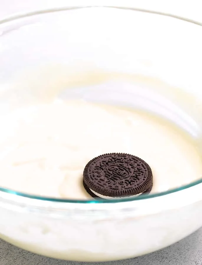 Glass bowl of pancake batter with one Oreo on top