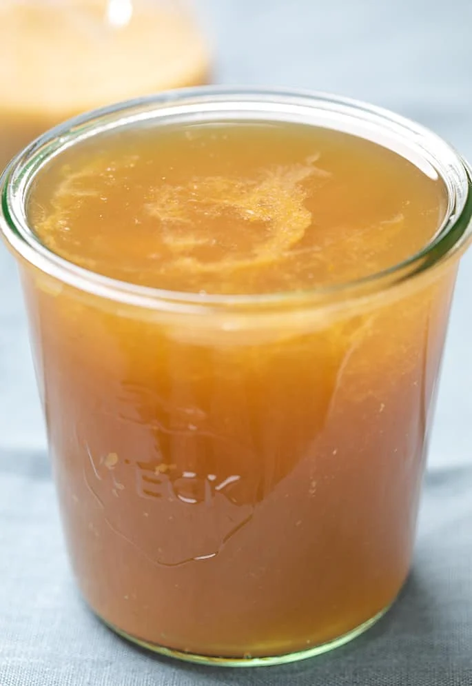 Glass jar with brown turkey drippings on blue cloth.
