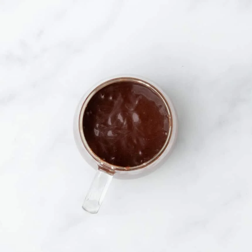 Glass mug filled with thick, glossy batter just before cooking.