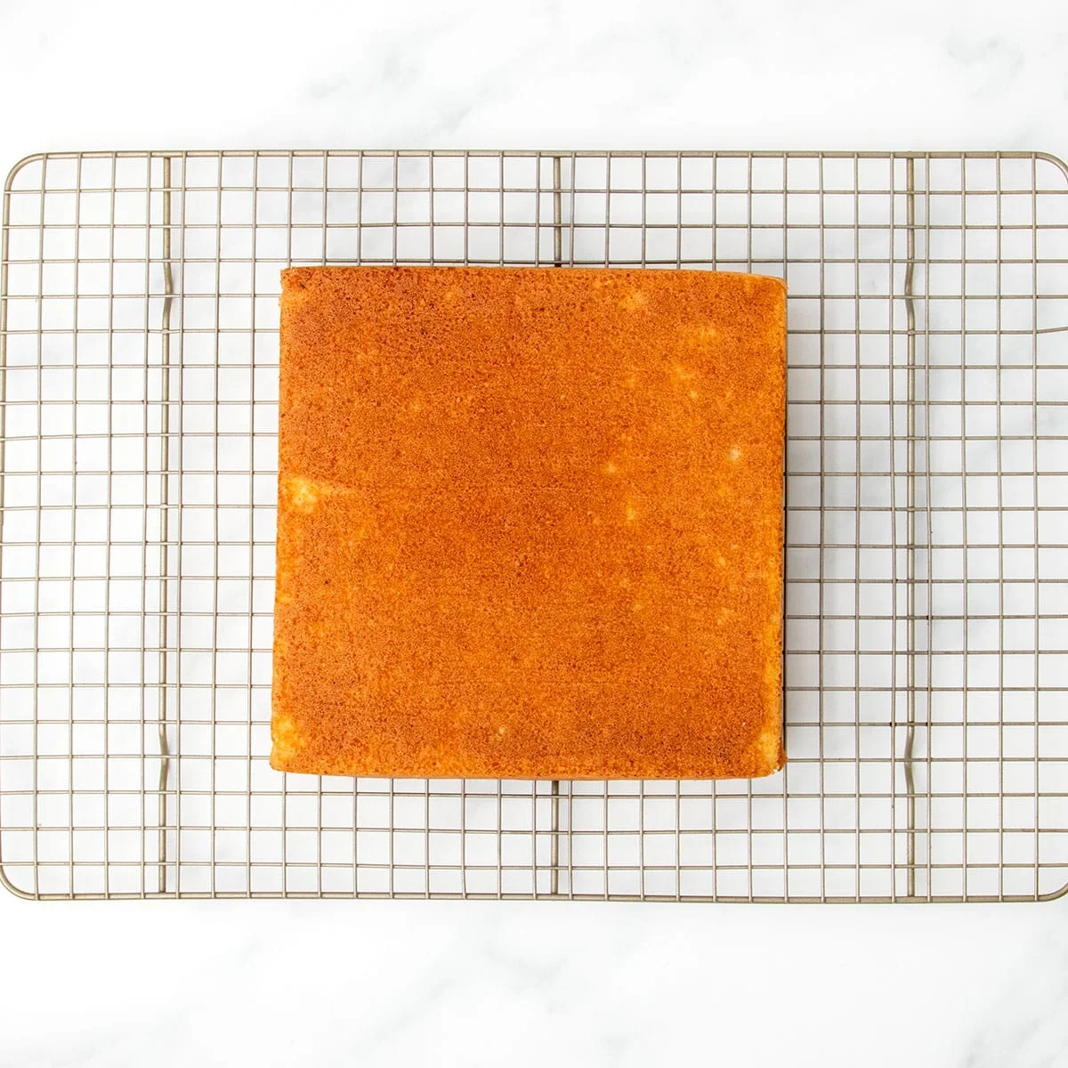 Golden baked square cake resting upside down on a wire cooling rack, just removed from the pan and cooling completely.